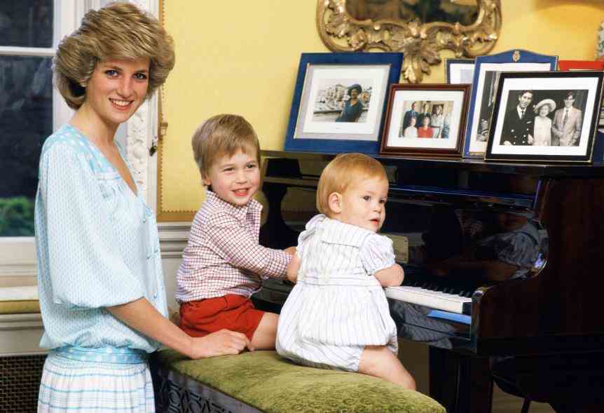 Prinzessin Diana lächelt, als Prinz Harry und Prinz William versuchen, Klavier zu spielen