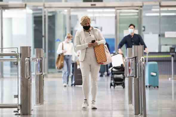 Passagiere, die von einem britischen Flug ankommen, gehen durch den Ankunftsbereich eines ausländischen Flughafens