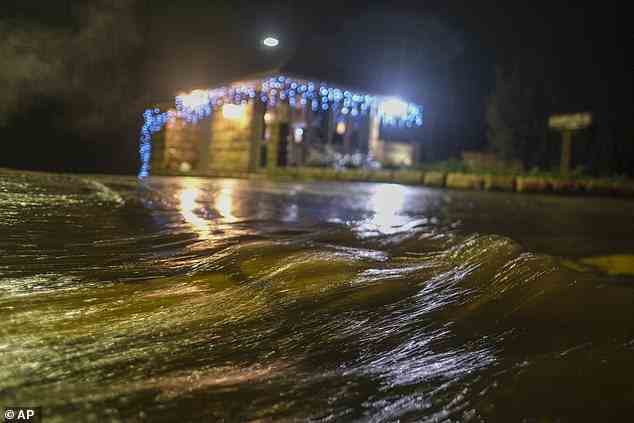 Water runs down a road in Montecito, California on Monday, January 9, 2023