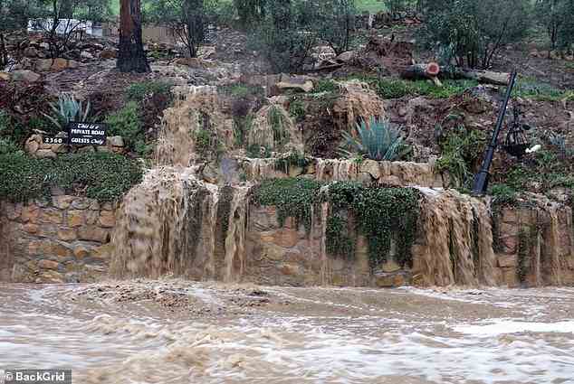 Brown water is seen gushing from gardens and homes in Montecito on Monday