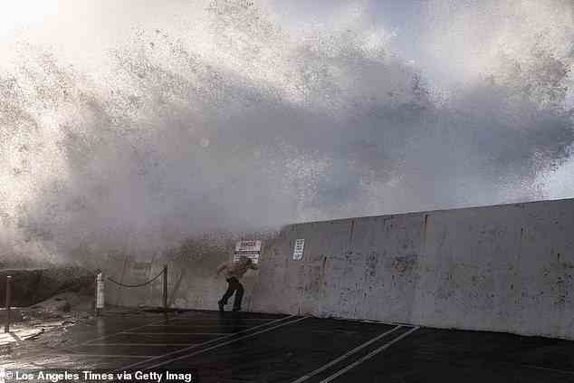 Pictured: A man runs from the spray of waves hitting and going over the breakwall of Redondo Beach, CA, Harbor, in the wake of a storm that cleared the south bay community of Los Angeles County, Thursday, January 5, 2023