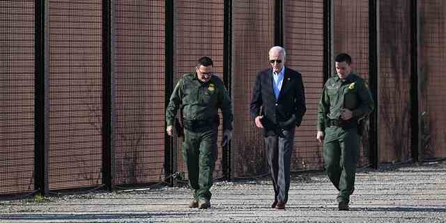 Präsident Joe Biden spricht mit einem Mitglied des Grenzschutzes, als sie am Grenzzaun zwischen den USA und Mexiko in El Paso, Texas, entlanggehen.