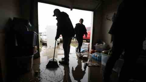 Randy Diaz fegt am 11. Januar 2023 in Planada, Kalifornien, Wasser aus der Garage des überfluteten Hauses seines Vaters. 