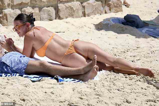 Die 24-jährige Modestudentin stellte ihren durchtrainierten Körper in einem knappen orangefarbenen Bikini zur Schau, als sie sich mit einem männlichen Freund im Sand entspannte