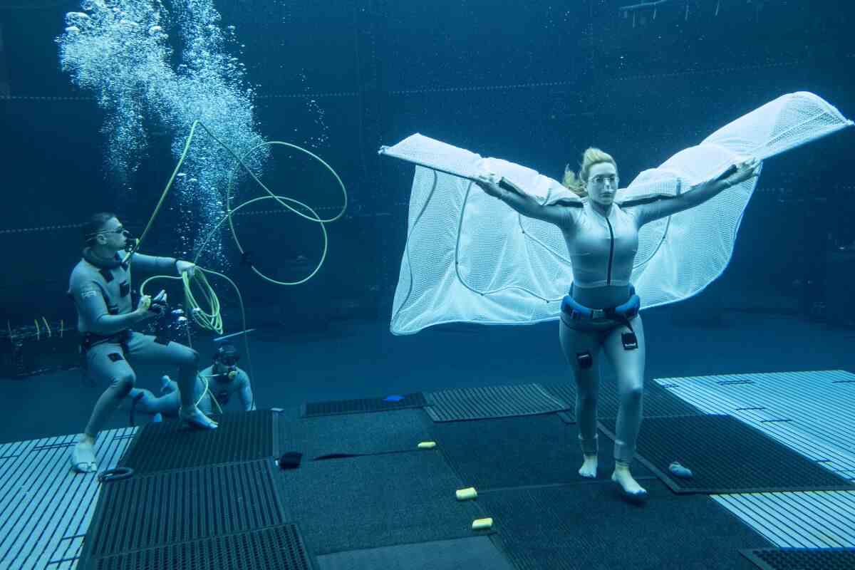 Filmteam in Neoprenanzügen filmt Kate Winslet bei einer Unterwasserszene.