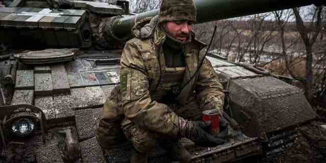 Ein ukrainischer Soldat hält am 12. Januar 2023 inmitten der russischen Invasion in der Ukraine eine selbstgebaute Grabenkerze, um provisorische Unterkünfte anzuzünden und zu heizen, und sitzt auf einem Panzer an der Front in der Nähe von Kreminna, Region Lugansk. 