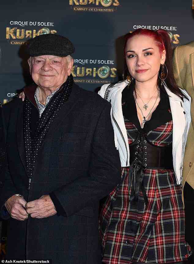 All smiles: Sophie Mae, 21, looked edgy in a tartan dress that nipped in at her waist with a corset-style belt and white leather jacket