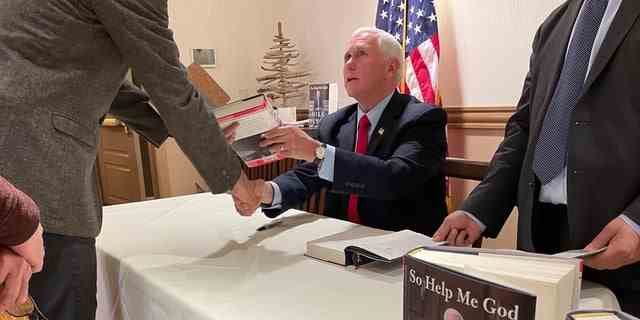 Former Vice President Mike Pence signs copies of his new autobiography "So Help Me God," at a book signing on Dec. 12, 2022, in Bedford, New Hampshire. 