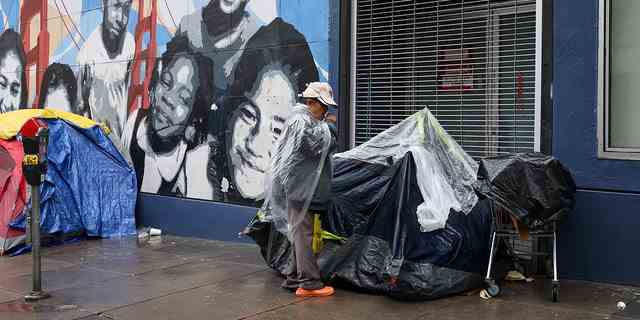 Obdachlose Zelte und eine obdachlose Frau werden am 13. Januar 2023 in der Nähe des Tenderloin District in San Francisco gesehen, als atmosphärische Flussstürme Kalifornien, USA, trafen. 