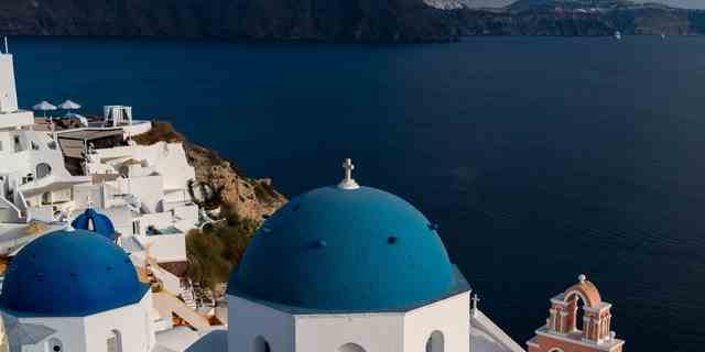 Ein Blick auf die Stadt Oia mit ihren Kalkhäusern und Kirchen mit blauen Kuppeln auf Santorini in der Ägäis.