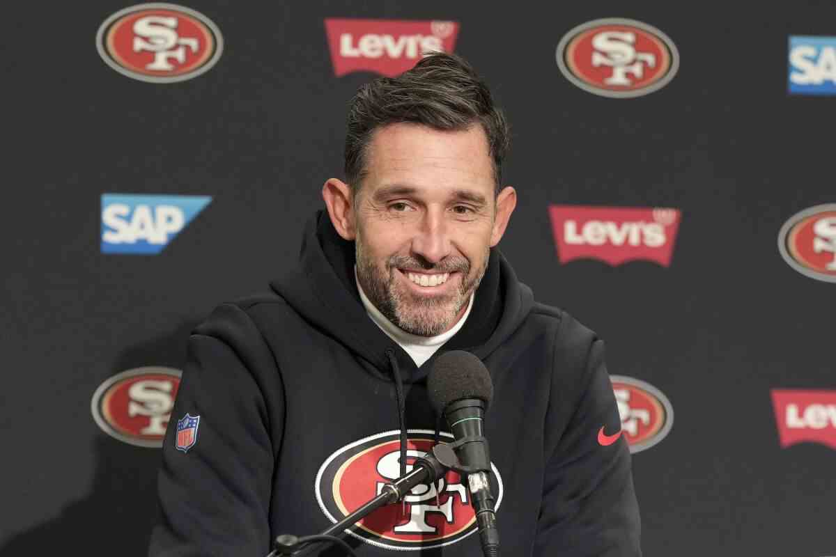 Kyle Shanahan, Cheftrainer der San Francisco 49ers, lächelt, während er auf einer Pressekonferenz spricht.