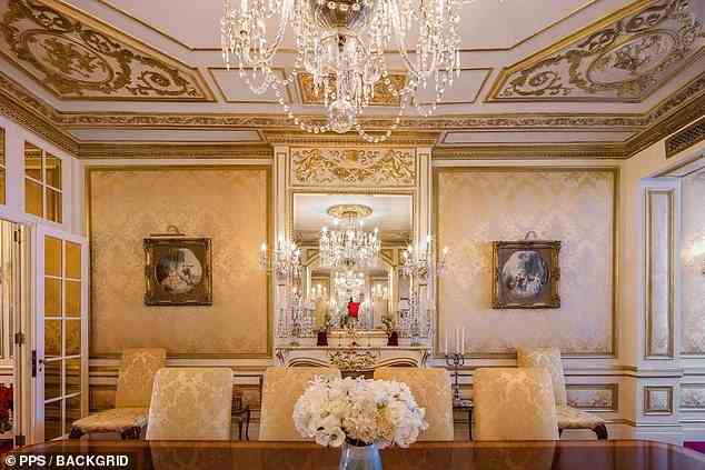Listing images also show a Versailles-inspired dining room with gold-tone wall coverings, ornate gold moldings and a woodburning fireplace which lay under a chandelier hanging from a ceiling dressed in more gilded moldings