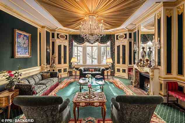 On the same level as the dining room stands a living room, boldly decorated in shades of red and emerald, underneath a gold fabric ceiling from which another chandelier hangs