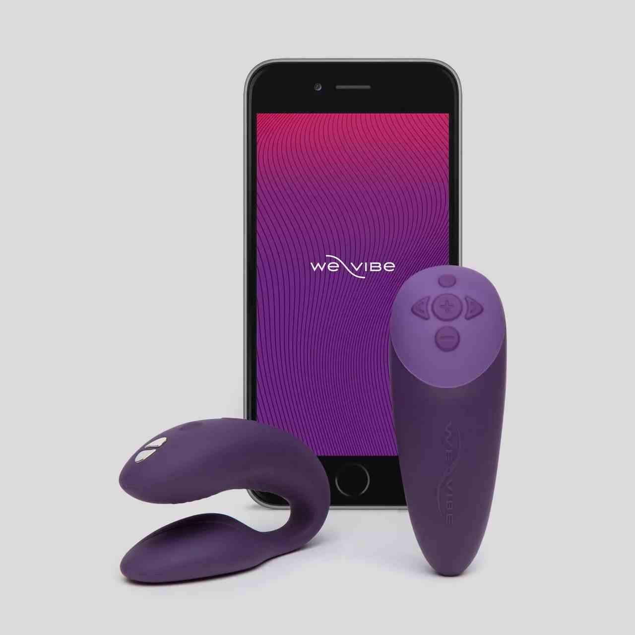 We-Vibe Chorus iPhone mit rosa bis violettem Hintergrund, zweizackigem violettem Vibrator und passender Fernbedienung auf grauem Hintergrund
