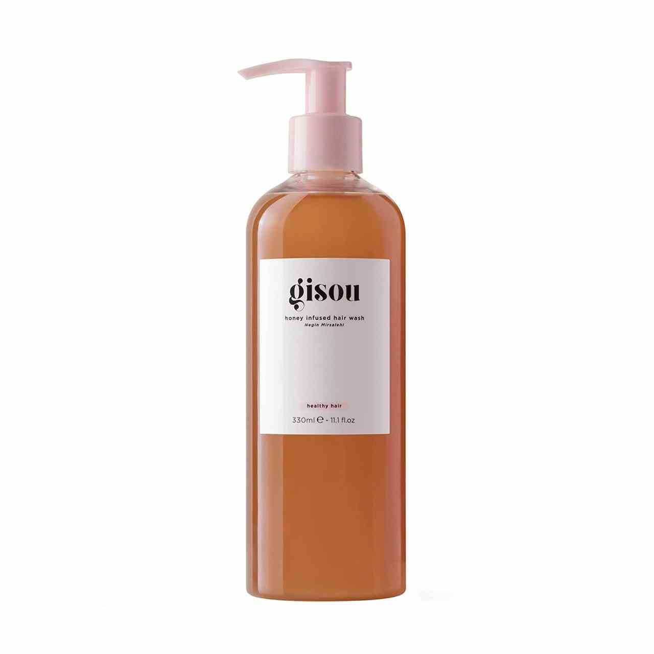 Gisou Honey-Infused Hair Wash Flasche bernsteinfarbenes Shampoo mit weißem Etikett und rosafarbener Pumpe auf weißem Hintergrund