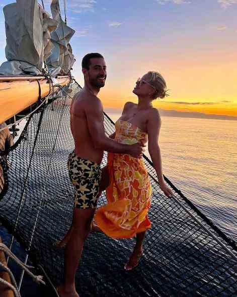 Sergio Carrallo und Caroline Stanbury posieren gemeinsam auf einem Boot bei Sonnenuntergang.