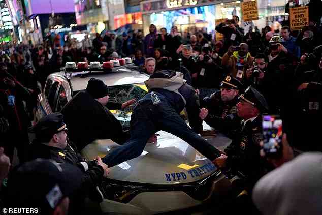 NYPD officers were soon after seen trying to drag him down from atop the vehicle and eventually arrested him