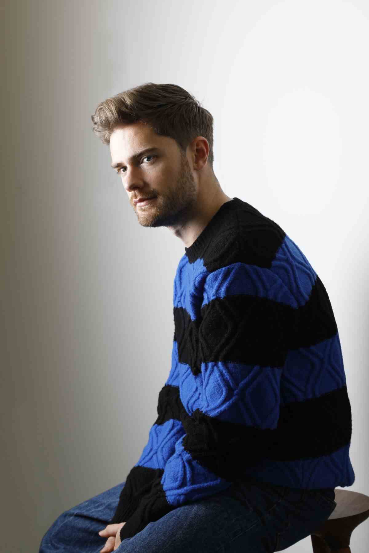Ein Mann in einem blau gestreiften Pullover blickt zur Seite.