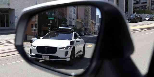 Ein autonomes Waymo-Fahrzeug spiegelt sich in einem Spiegel wider, als es am 11. April 2022 in San Francisco, Kalifornien, entlang der California Street fährt. 