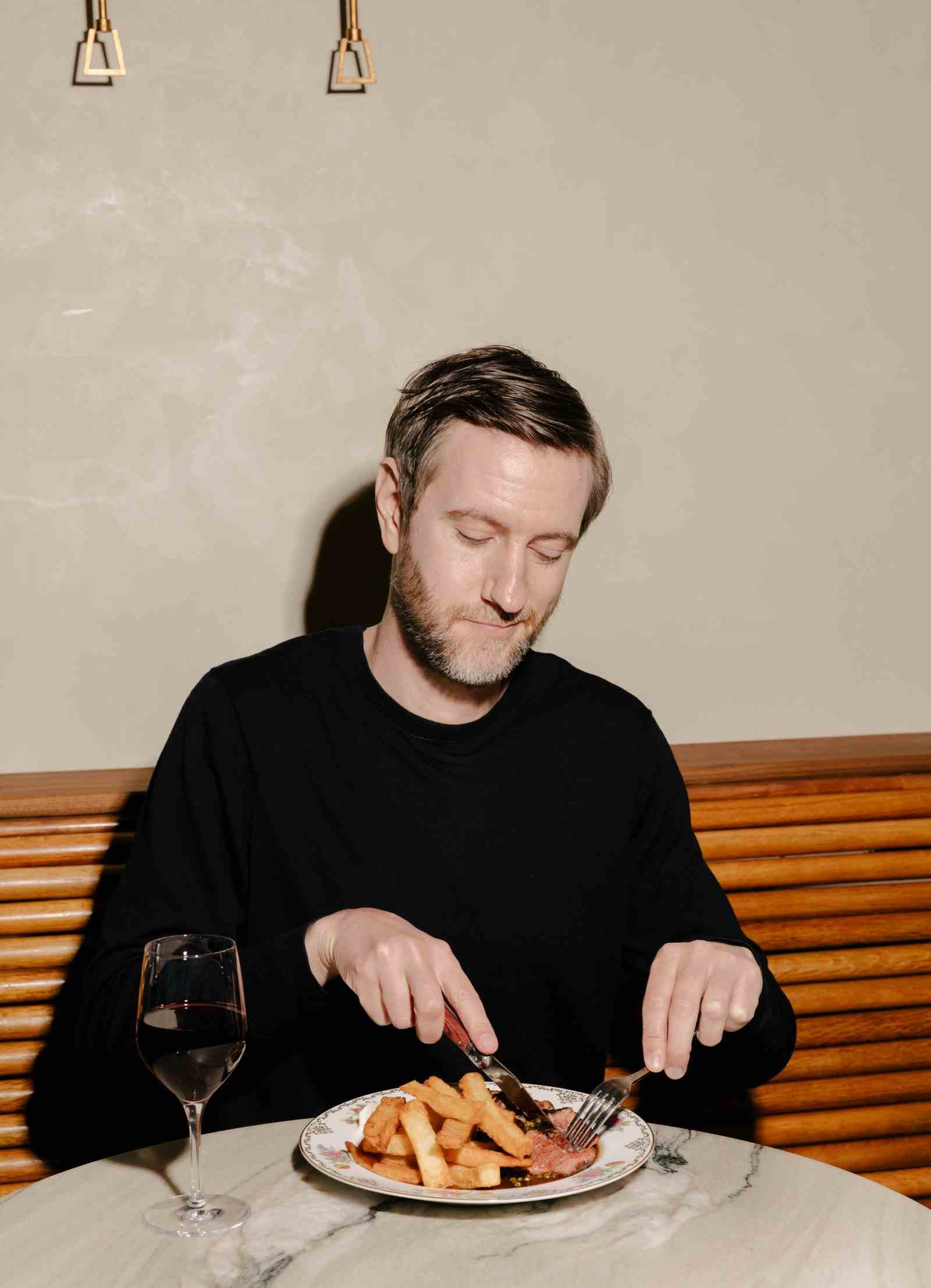 Ein Mann schneidet englische Chips mit Sirloin au poivre in ein Gericht.