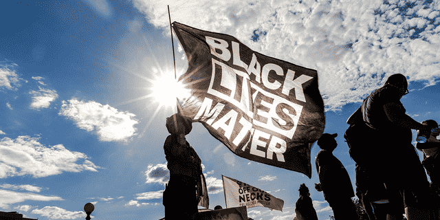 Eine Frau hält während einer Veranstaltung zum Gedenken an George Floyd eine Black-Lives-Matter-Flagge.