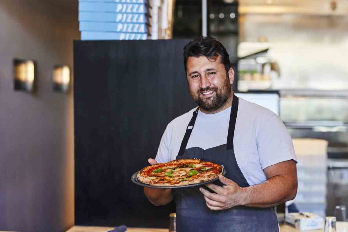 Pizzana-Koch Daniele Uditi hält in seinem Restaurant eine mit Basilikum belegte Pizza.