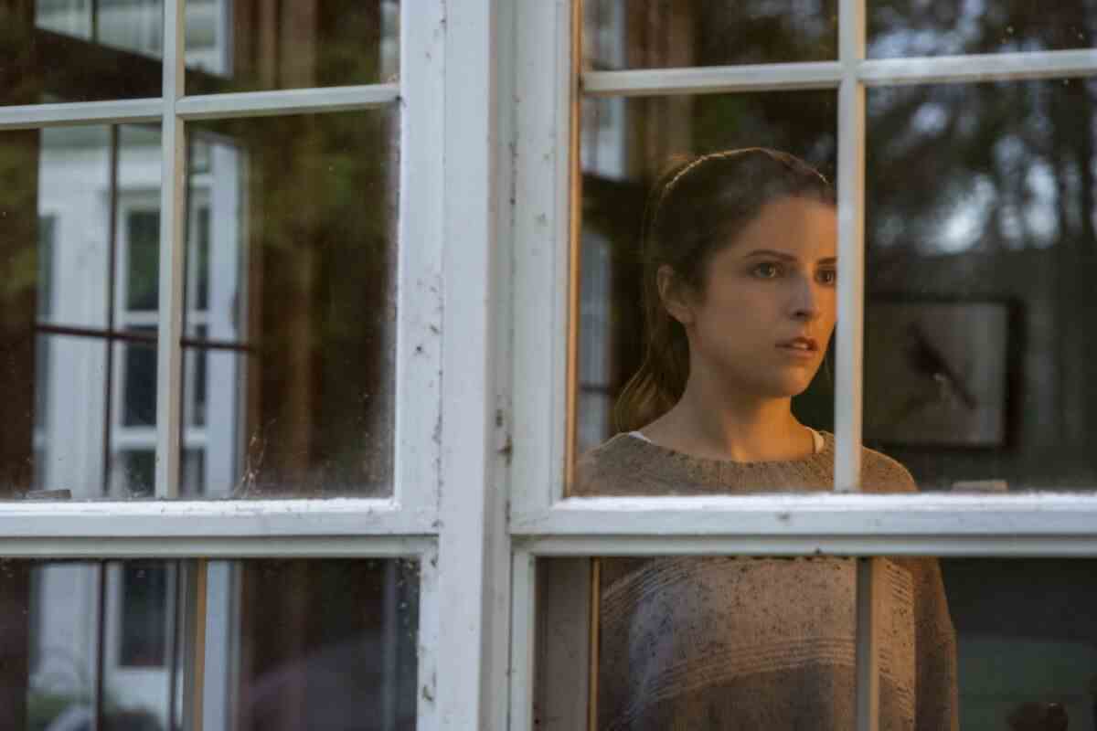 Eine Frau schaut ängstlich durch Fensterscheiben, die Zellengittern ähneln.