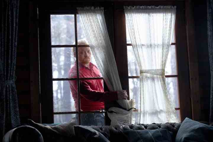 Rupert Grint steckt in einer Szene aus Knock at the Cabin seine Hand durch eine kaputte Tür.