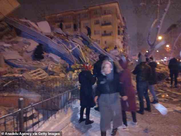 Bewohner eines eingestürzten Gebäudes in Maltaya, Türkei, sehen geschockt zu