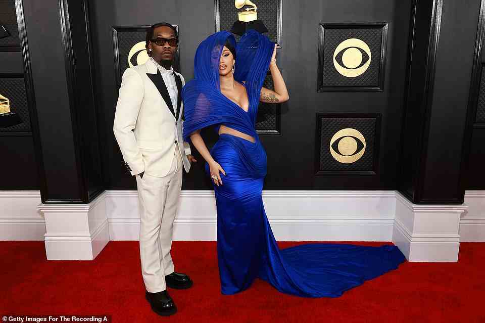 Breathtaking: Cardi B flashed her midriff and cleavage in a dark blue gown, which featured a head covering; she arrived with husband Offset