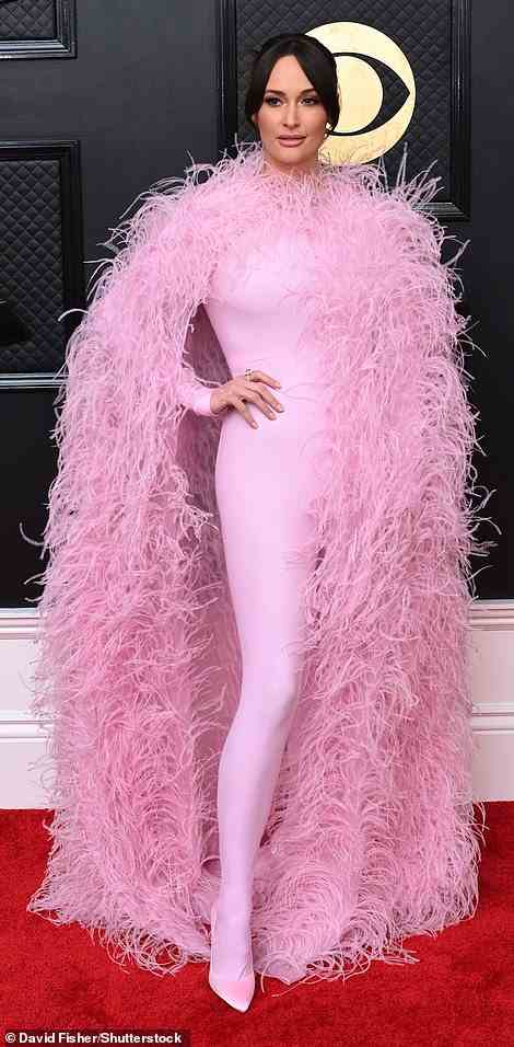 Bold and bright: Kacey Musgraves wowed in a cotton candy pink jumpsuit and matching feathered cape; the country artist added pink pumps to complete her bright look