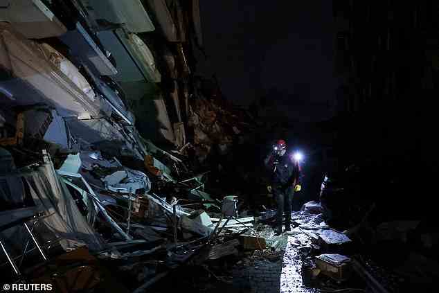 Ein Rettungshelfer geht am Montagabend nach dem Erdbeben neben eingestürzten Gebäuden in Antakya, Türkei