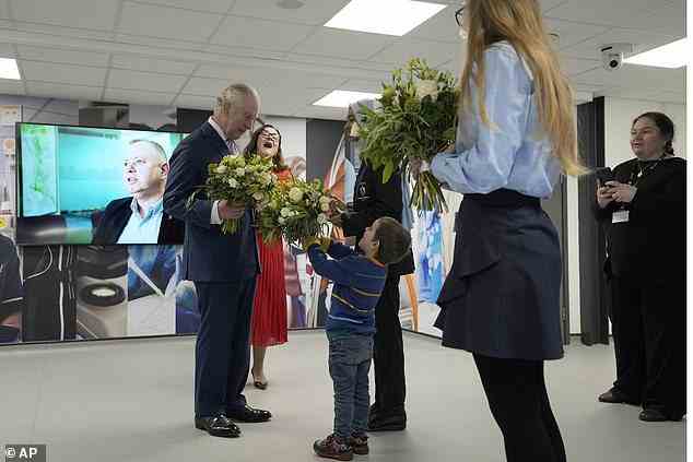 King Charles eröffnete auch sein neues medizinisches Lehrzentrum an vorderster Front.  Abgebildet, wie sie einen Blumenstrauß von einem jungen königlichen Fan entgegennimmt