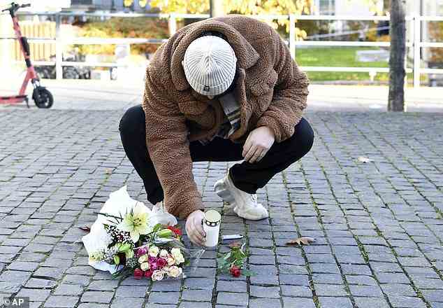 A man places a candle and flower tribute near the site where Swedish rapper Einar was shot