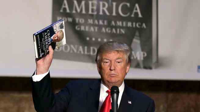 Donald Trump hält ein Buch in der Hand