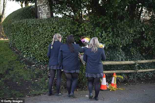 Drei Mädchen in Schuluniform hinterlassen Blumen und Ehrungen für Brianna Ghey in der Nähe ihres Todesortes