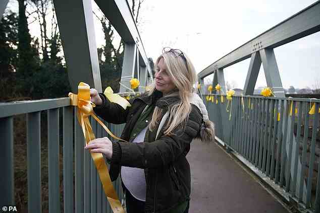 Charlotte Drake, the next-door neighbour and friend of Nicola Bulley, ties a yellow ribbon with a message of hope written on it, to a bridge over the River Wyre in St Michael's on Wyre today