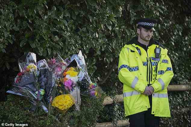 Ein Polizist steht neben floralen Ehrungen am Eingang zum Linear Park, wo die 16-jährige Brianna Ghey gefunden wurde