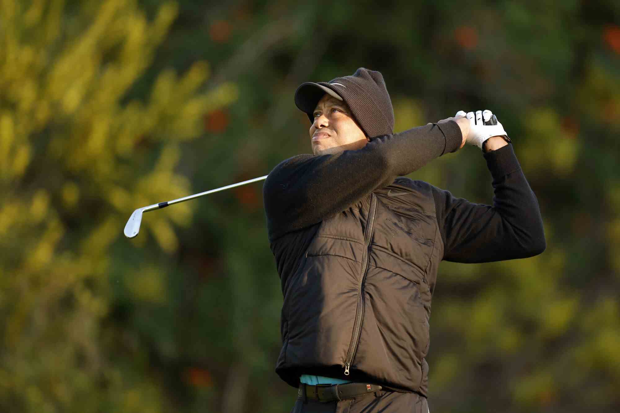 Tiger Woods, gegen die Kälte gebündelt, folgt mit einem Abschlag