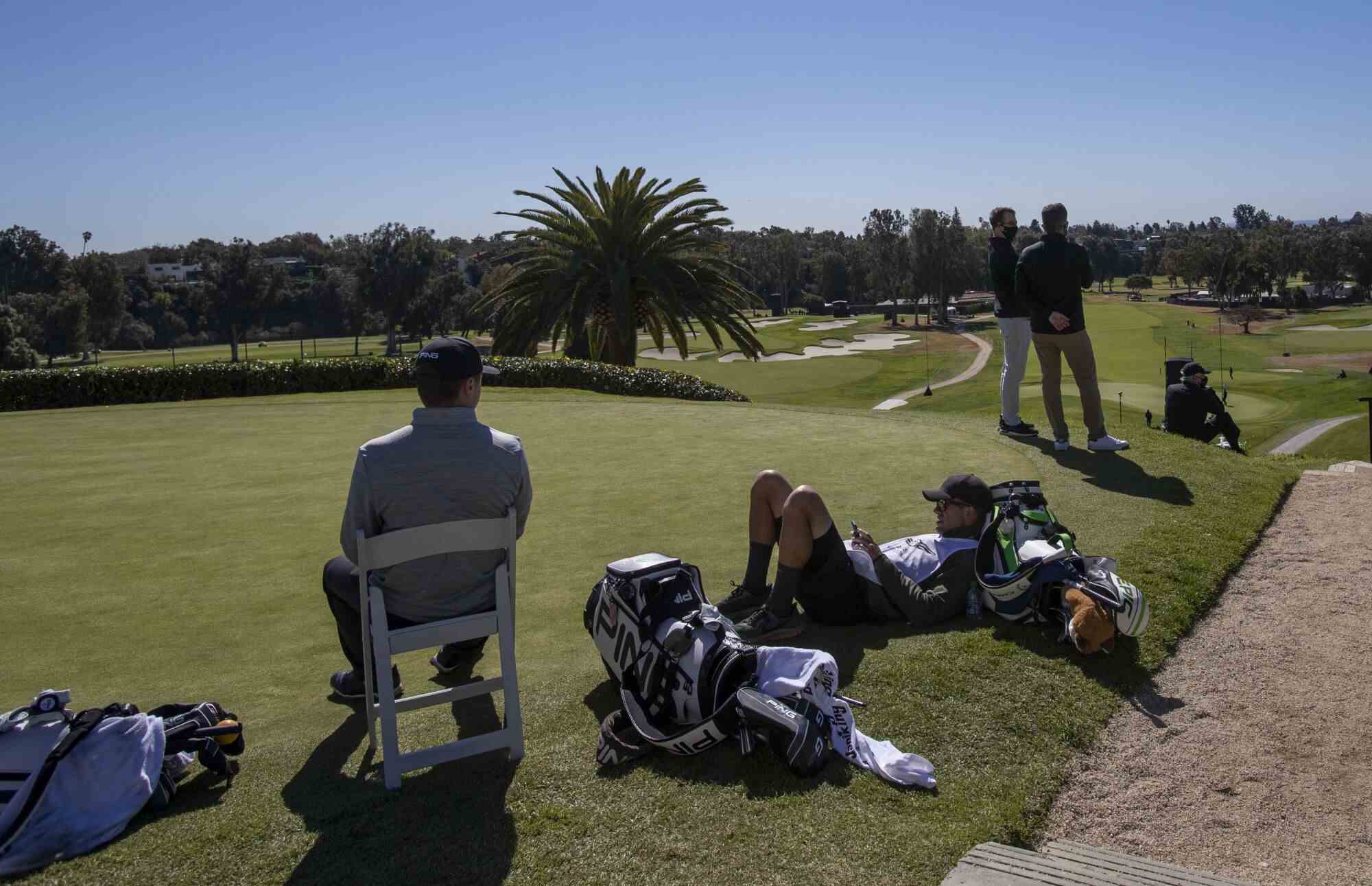 Golfer und ihre Caddies entspannen sich auf einer Abschlagbox
