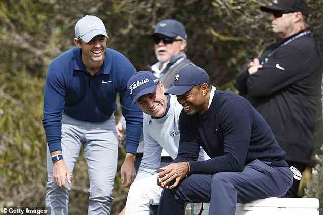 Woods smiles alongside playing partners McIlroy (L) and Justin Thomas (C) on the fourth tee