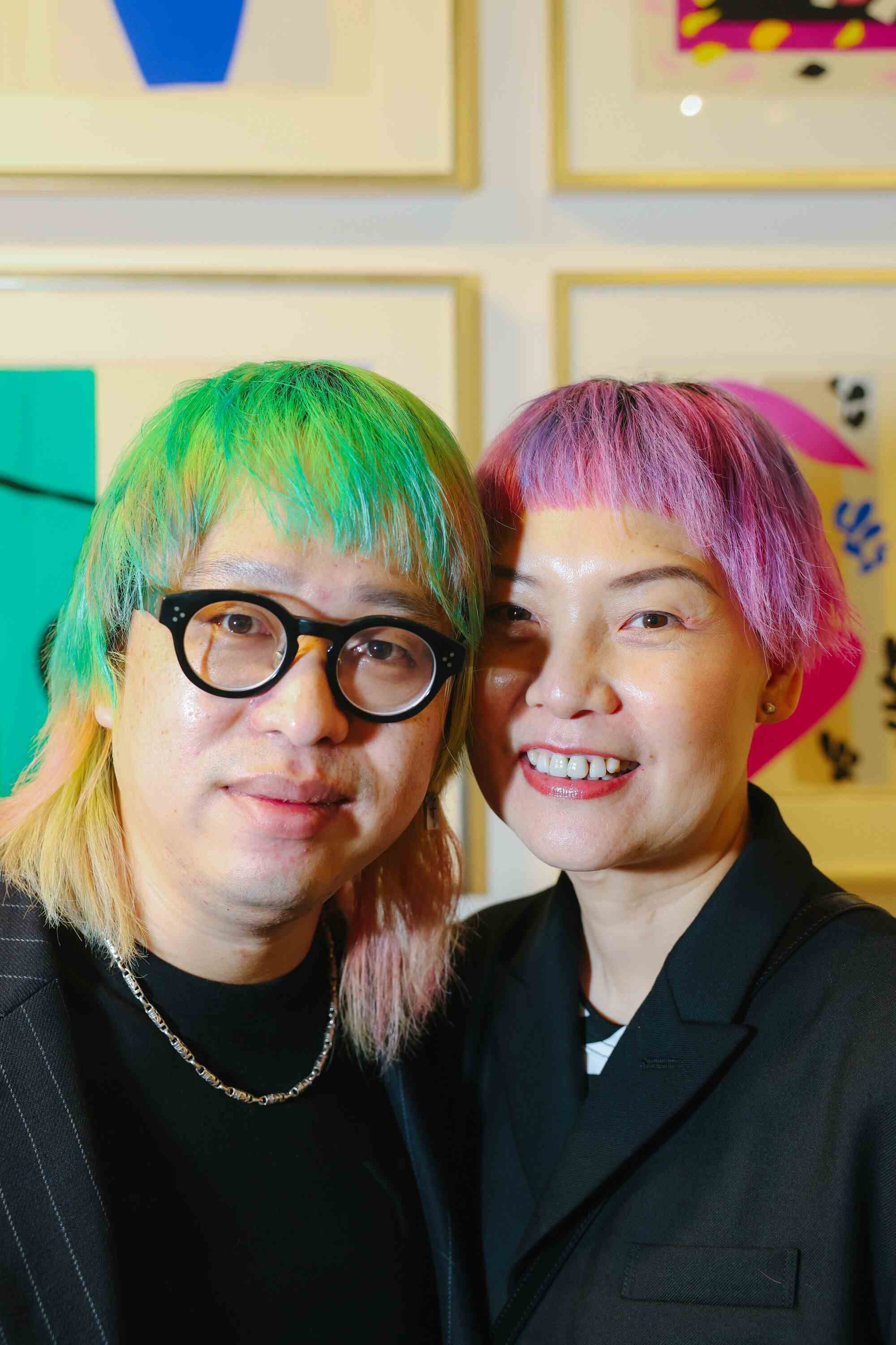 Zwei Personen mit gefärbten Haaren (grün, links und rosa) posieren für ein Foto.