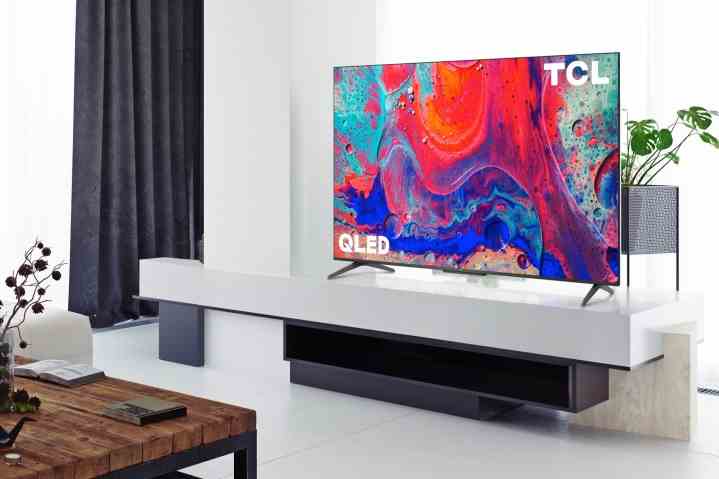 Der 4K QLED Google TV der TCL 5-Serie befindet sich auf einem Entertainment-Center in einem Wohnzimmer.