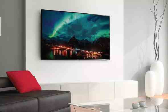 Ein 65-Zoll-4K-Fernseher der Klasse 4 von TCL an einer Wohnzimmerwand mit einem Bild der Nordlichter auf dem Bildschirm.