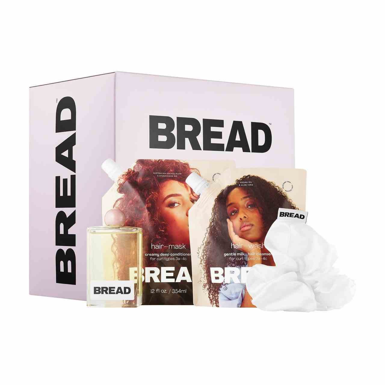 Bread Beauty Supply Wash-Day Essentials Kit Lavendelbox, rechteckige Flasche Haaröl, zwei Beutel Haarmaske und weißer Scrunchie auf weißem Hintergrund