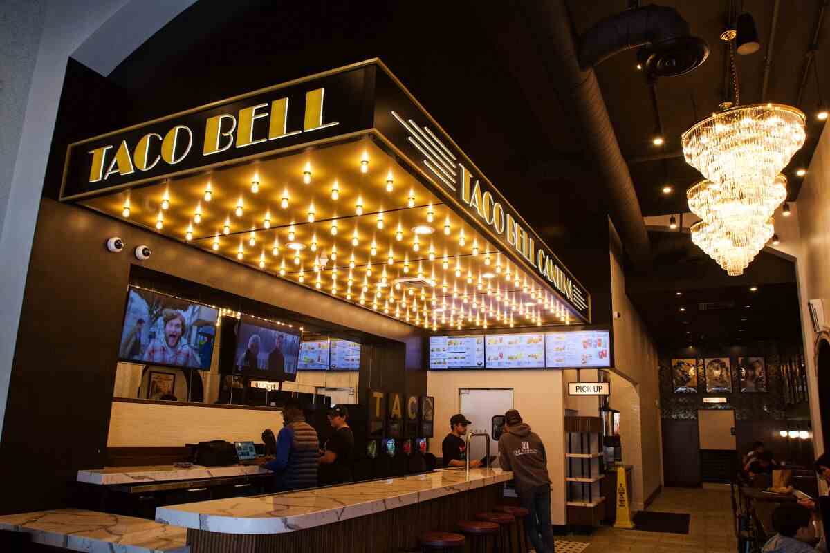 Ein Innenraum von Taco Bell Cantina;  Auf der linken Seite, über der Bar, befindet sich ein künstliches Kinozelt, das von Reihen von Glühbirnen beleuchtet wird.