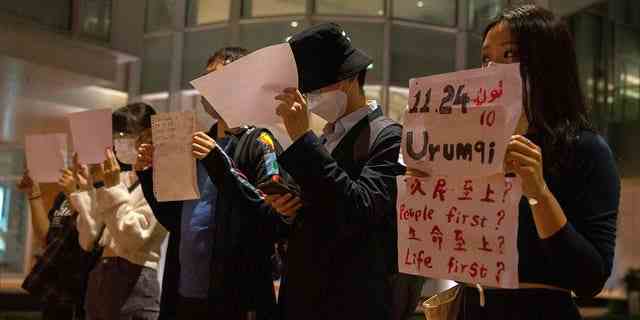 Demonstranten halten während einer Versammlung an der Universität von Hongkong in Hongkong am Dienstag, den 29. November 2022, weißes Papier mit Schriften zum Gedenken an das tödliche Feuer in Urumqi vom 24. November hoch.