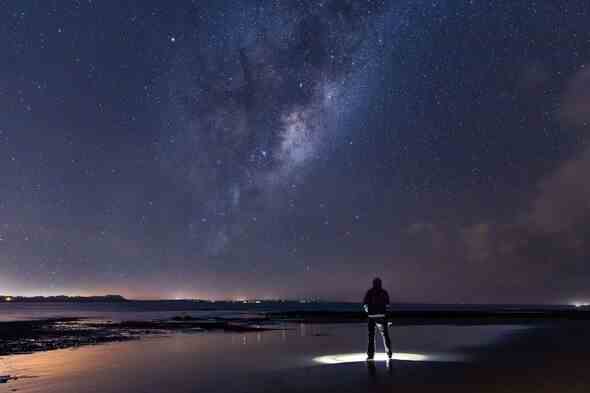 Ein Mann betrachtet einen Nachthimmel voller Sterne