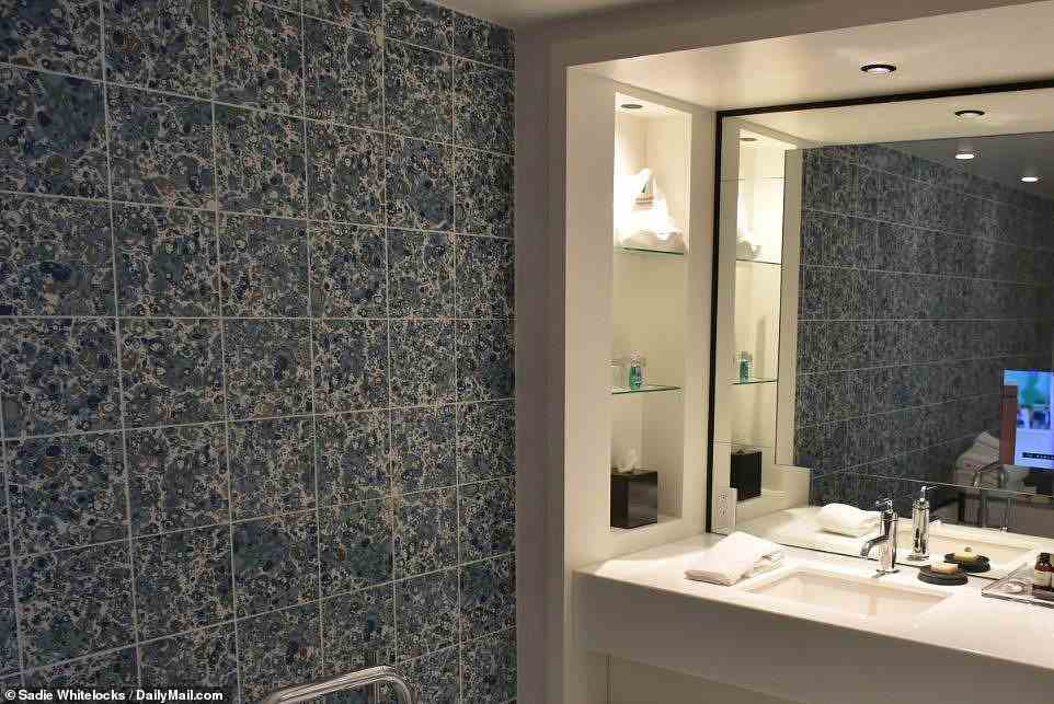 One of the bathrooms in the suite features snazzy tiling and a TV screen built into the mirror 