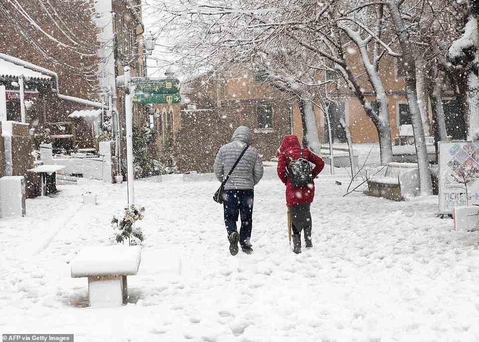 Zwei Menschen gehen am Montag während eines heftigen Schneefalls auf der spanischen Baleareninsel Mallorca eine schneebedeckte Straße im Bergdorf Valldemossa entlang